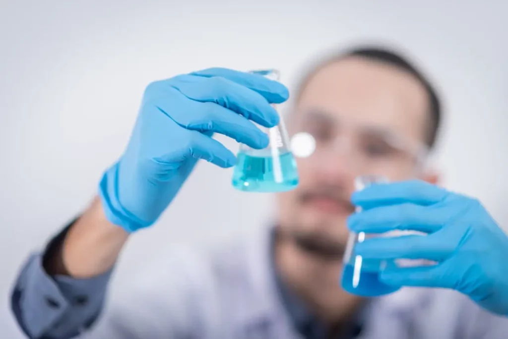 Picture of a researcher inspecting beakers and using PEGs in fluorescent polymer gels.
