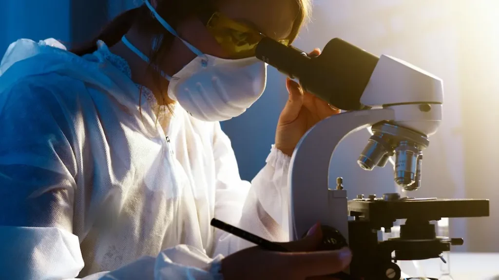 Picture of a scientist looking into a microscope for PEGylation service quality check.